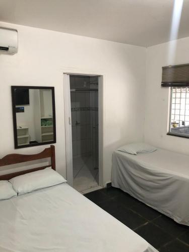 a bedroom with two beds and a glass shower at Pousada Irmão Sol Irmã Lua in Abadiânia