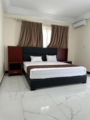 a bedroom with a large bed and a window at Melias Hotel Diamniadio in Dogar