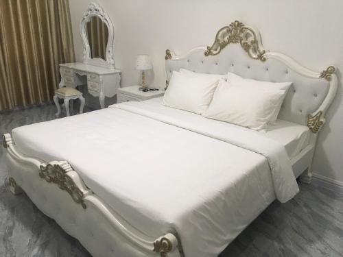 a bedroom with a white bed with a gold and white headboard at DONG PHUONG HOTEL in Bao Loc