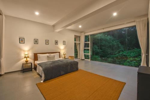 ein Schlafzimmer mit einem Bett und einem großen Fenster in der Unterkunft Tea Heritage in Urulewatta