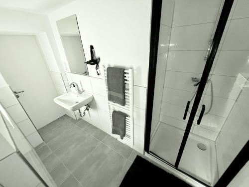 a white bathroom with a sink and a shower at City-Apartment für Familien 5 Per, 8 Min zum Hbf! in Mönchengladbach