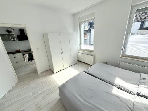 a white bedroom with a bed and two windows at City-Apartment für Familien 5 Per, 8 Min zum Hbf! in Mönchengladbach