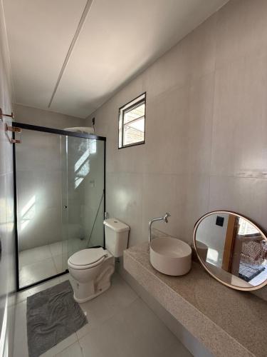 a bathroom with a toilet and a sink and a mirror at Nossos Chalés de Praia in Bragança