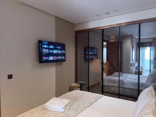ein Schlafzimmer mit einem Bett und einem Fernseher an der Wand in der Unterkunft Stylish Apartment with a seaview 9 in Casablanca
