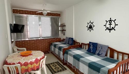 ein Zimmer mit zwei Betten und einem Tisch und einem Fenster in der Unterkunft Apartamento Pé na Areia - Praia Grande in Praia Grande