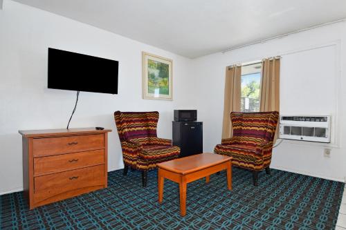 a room with two chairs and a tv and a dresser at Budget Motel in Portland