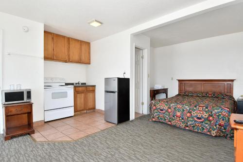 a bedroom with a bed and a kitchen with a refrigerator at Budget Motel in Portland