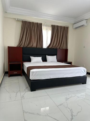 a bedroom with a large bed in front of a window at Melias Hotel Diamniadio in Dogar