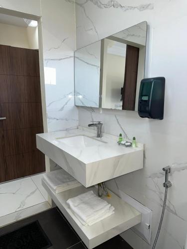 a white bathroom with a sink and a mirror at Melias Hotel Diamniadio in Dogar