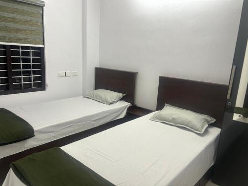 two twin beds in a room with a window at Samriddhi Homestay in Trivandrum