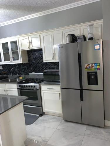una cucina con frigorifero in acciaio inossidabile e mobili bianchi di Border love apt 3 a Kingston