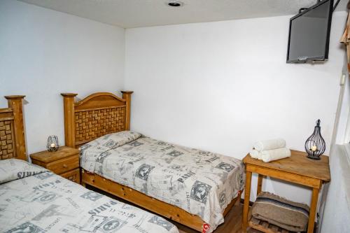 a bedroom with two beds and a flat screen tv at Hostal Makea Pachuca in Pachuca de Soto