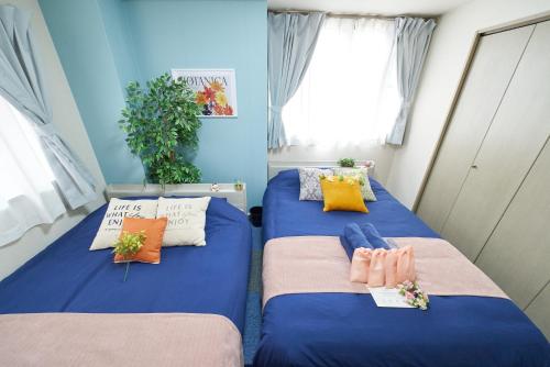 two beds in a room with blue walls at AO101 - Tokyo Stay Spacious Apartment Direct Train to Narita & Asakusa in Tokyo