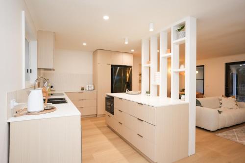a kitchen with white cabinets and a living room at Capel Sound Beach House Steps to Sand in Capel Sound