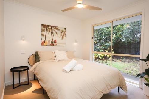 a bedroom with a large bed with a window at Capel Sound Beach House Steps to Sand in Capel Sound