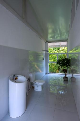 a white bathroom with a toilet and a window at Tea Heritage Colonial Luxury Retreat Kandy in Urulewatta