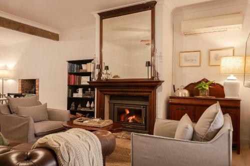 a living room with a fireplace and a mirror at Tweedies Gully Estate Settlers Cottage Barossa in Williamstown
