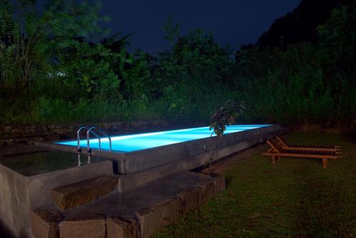 ein Swimmingpool bei Nacht mit einer Bank daneben in der Unterkunft Tea Heritage in Urulewatta