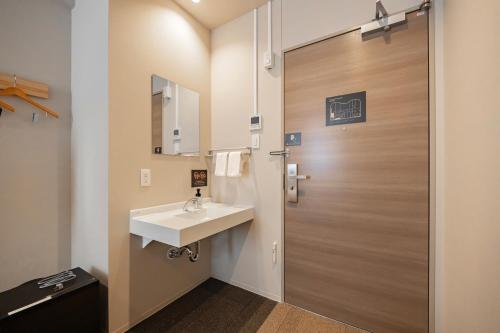 a bathroom with a sink and a door at GRAND HOSTEL LDK Tokyo Nishikasai -GRAND OPENING In May 2025- in Tokyo