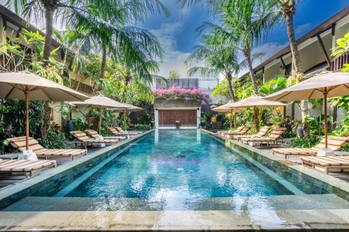 a pool with chairs and umbrellas at a resort at Kejora Suites in Sanur
