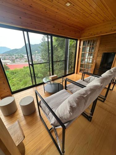 ein Wohnzimmer mit Couch und großem Fenster in der Unterkunft Retreat Camp Mahoroba in Fujikawaguchiko