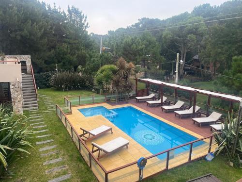 une piscine avec une terrasse et des chaises longues autour dans l'établissement Departamento muy cerca del mar, à Mar de las Pampas