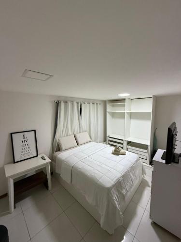 a bedroom with a large white bed and a television at Duplex panorâmico in Vitória da Conquista