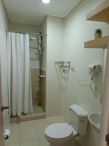 a white bathroom with a toilet and a shower at Hills Staycation by SDC in Manila
