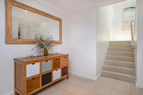 a mirror on a dresser in a hallway with a staircase at Sunset and Surfside in Yallingup