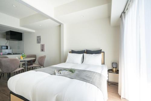 a bedroom with a large white bed and a table at Daffitto Honjo Azumabashi in Tokyo