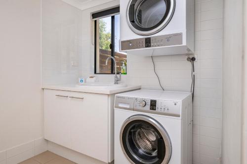 a white laundry room with a washing machine and a sink at Sunset and Surfside in Yallingup
