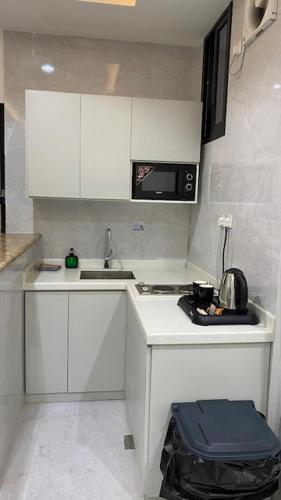 a small white kitchen with a sink and a microwave at بالمز للشقق المخدومه in Sufan