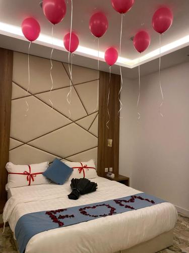 a bedroom with pink balloons hanging above a bed at بالمز للشقق المخدومه in Sufan