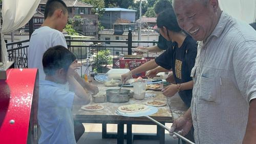 a group of people standing around a table making pizzas at Beijing MutianyuGreat Wall Let'sgo Hotel&Bar in Huairou