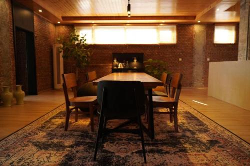 a dining room with a table and chairs on a rug at Beijing MutianyuGreat Wall Let'sgo Hotel&Bar in Huairou