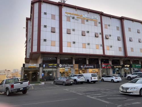 a large building with cars parked in a parking lot at كــيــان الـمـنـسـك Kayan Al Mansak in Abha