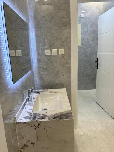 a bathroom with a sink and a mirror at شقق الاطاولة المفروشة in Āl Ţāwilah