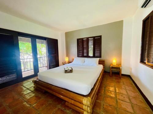 a bedroom with a bed with white sheets and two windows at The Ananyana Beach Resort by SMS Hospitality in Panglao