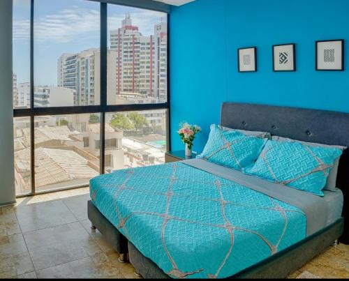 a blue bedroom with a bed and a large window at Alojamiento en hermoso apartamento vita 945 in Gaira
