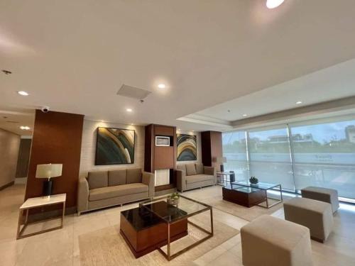 a living room with couches and tables in a building at Furnished Condo Unit-Green2 PoolWifiNetflix in Dasmariñas
