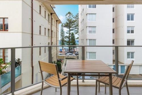 a balcony with a wooden table and chairs at The Sebel Sydney Manly Beach in Sydney