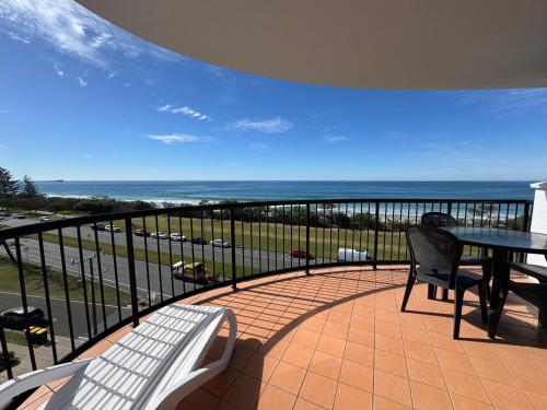 a balcony with a table and chairs and the ocean at Absolute Beachfront Penthouse with Exclusive Rooftop in Alexandra Headland