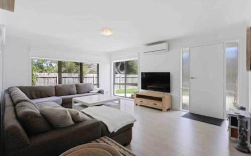 a living room with a couch and a flat screen tv at Beach House Getaway 2 in Smiths Beach