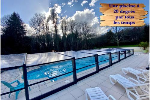 - une piscine avec des chaises et un panneau à côté dans l'établissement Gîte Breizh piscine ou jacuzzi, à Saint-Évarzec