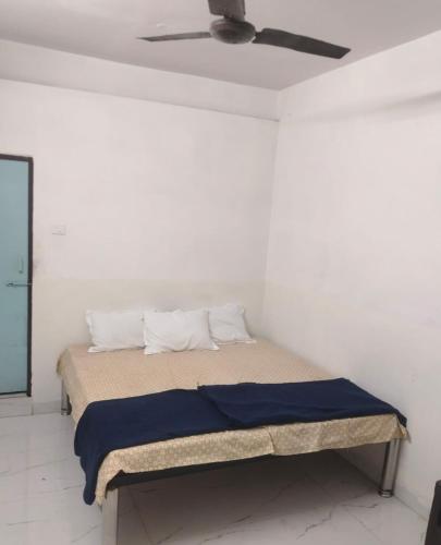 a bed in a white room with a ceiling fan at Comfi Stay Hotel Bhopal in Bhopal