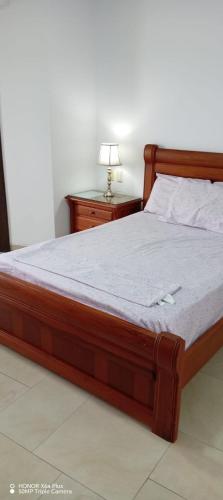 a bed with a wooden frame and a lamp on a table at MAKANA Tonsupa - Suites y Departamentos Familiares - Deluxe Suites in Tonsupa