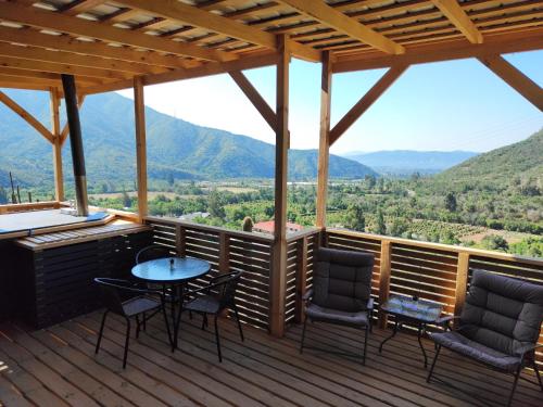 a deck with a table and chairs and mountains at Posada Vista Hermosa Colibri in Lo Narváez