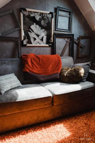 - un canapé dans le salon avec une couverture orange dans l'établissement Les Aires en Scènes au bord de l'eau, à Épagne-Épagnette