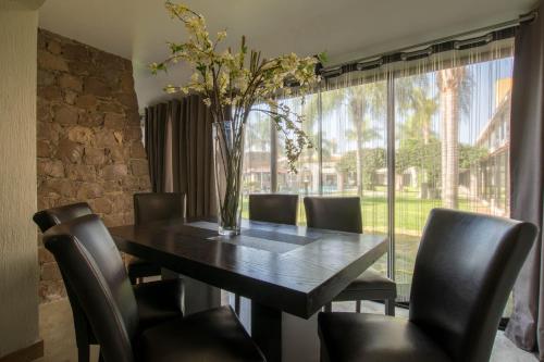 a dining room table with chairs and a vase with flowers at Real de Minas Poliforum in León