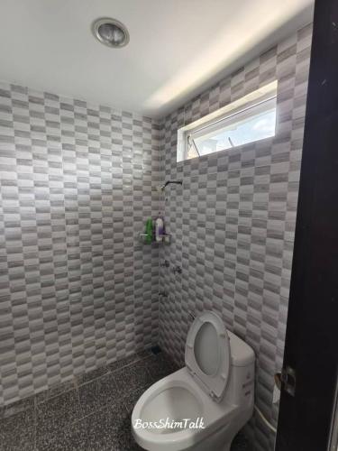 a bathroom with a white toilet and a window at Serene Stay- Kuching City Single Storey SemiD in Kuching